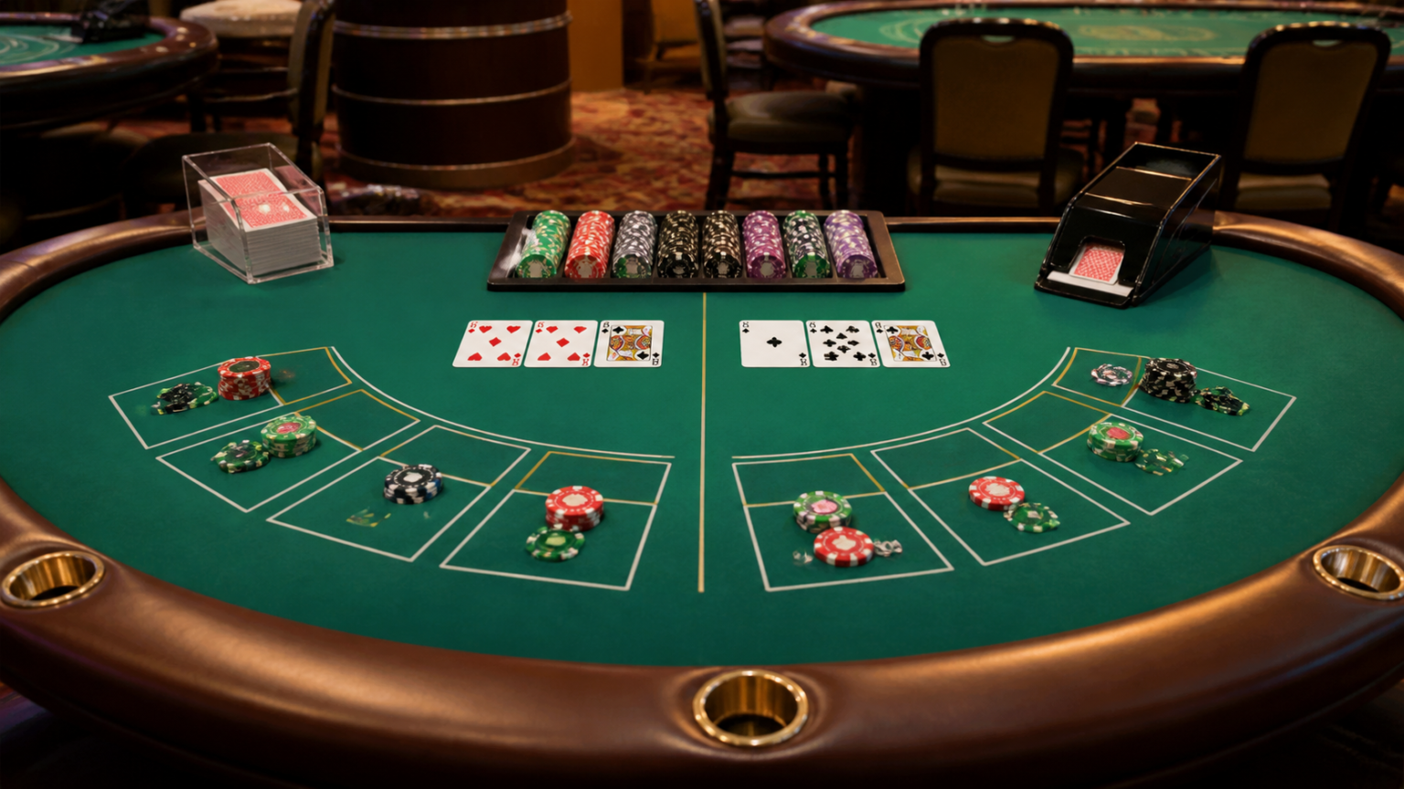 Bàn baccarat với bài và phỉnh trên mặt nỉ xanh trong sòng bạc